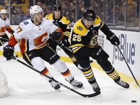 Calgary Flames' Mark Jankowski (77) battles Boston Bruins' Brandon Carlo (25) for the puck during the third period of an NHL hockey game in Boston, Tuesday, Feb. 13, 2018. The Bruins won 5-2. (AP Photo/Michael Dwyer) ORG XMIT: MAMD109