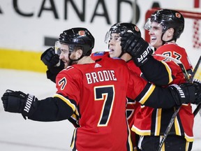 Flames forward Sean Monahan celebrates his game-winning goal with teammates T.J. Brodie, left, and Johnny Gaudreau during overtime NHL hockey action against the Chicago Blackhawks in Calgary on Saturday. Photo by Jeff McIntosh/The Canadian Press.