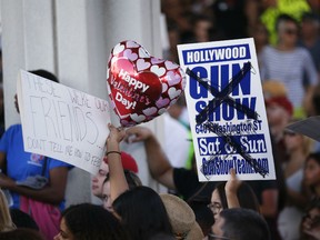 Demonstrators hold a sign that against a gun show in Hollywood, Fla., during a protest against guns on the steps of the Broward County Federal courthouse in Fort Lauderdale, Fla., on Saturday, Feb. 17, 2018. The Florida school shooting has created an outpouring of anger from students who survived the shooting, many of whom have publicly blamed President Donald Trump and NRA-supported politicians for creating the conditions that led to the shooting.