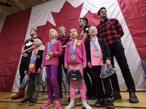 Students wear the medals of, back row left to right, Justin Kripps, Alex Gough, Justin Snith, and Sam Edney, as they sing the national anthem during a celebration of the 2018 Pyeongchang Olympics at Holy Name School in Calgary, Alta., Wednesday, Feb. 28, 2018. THE CANADIAN PRESS/Jeff McIntosh ORG XMIT: JMC104