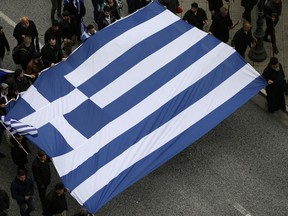 Protesters hold a Greek flag ahead of a rally in central Athens, Sunday, Feb. 4, 2018.
