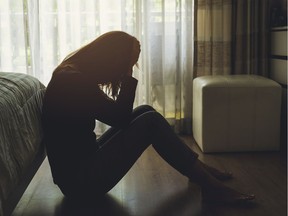 depressed woman sitting head in hands in the dark bedroom