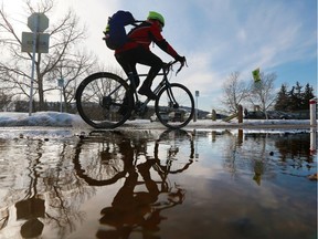 A cyclist is reflected in a puddle of melting snow on the Bow River pathway near Edworthy Park on a warm second official day of spring, Wednesday March 21, 2018.  However, the weather is taking a temporary turn for the worse today, with snow expected. Gavin Young/Postmedia
