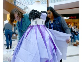 Maia Kowal and Aditi Sitolay work on their paper only fashion dress at Southcentre Mall on Saturday.