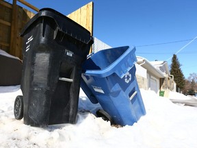 A City of Caglary black bin used to collect garbage and a blue bin for recycling, are shown in an alley in Acadia in Calgary on Saturday, March 10, 2018.