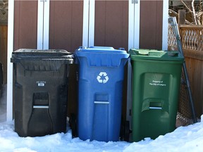 A City of Caglary black bin used to collect garbage, a blue recycling bin and a green bin for ffood and yard waste, are shown in an alley in Acadia in Calgary on Saturday, March 10, 2018. A city committee will look at hiking monthly rates for the black cart garbage pickup service by $4 to $5 and charging currently fully subsidized condo dwellers.Jim Wells/Postmedia