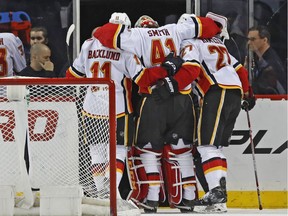Calgary Flames goaltender Mike Smith (41) is helped off the ice by Flames teammates Mikael Backlund (11), of Sweden, and defenseman Dougie Hamilton (27) after Smith was injured during the third period of an NHL hockey game against the New York Islanders in New York, Sunday, Feb. 11, 2018. The Flames defeated the Islanders 3-2 on Matthew Tkachuk's game-winning goal. Tkachuk