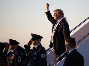 President Donald Trump gestures to people cheering him across the tarmac as he, arrives on Air Force One with first lady Melania Trump and their son Barron Trump at Palm Beach International Airport, in West Palm Beach, Fla., Friday, March 23, 2018.