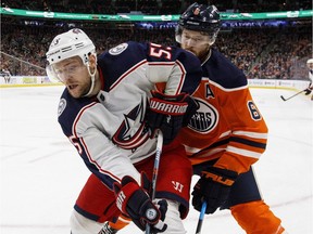 Columbus Blue Jackets centre Mark Letestu and Edmonton Oilers defenceman Adam Larsson battle for the puck during first period NHL action in Edmonton on March 27, 2018.