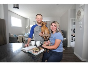 Eryn and Jamie Miller pose with their dogs Lika the Yorkie and Cashie a miniature Pinscher in their new home by Stepper Homes  in the Cochrane community of Heritage Hills.