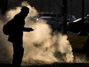 FILE - In this Nov. 30, 2012 file photo, a pedestrian looks at his phone near steam vented from a grate near the Philadelphia Museum of Art on a cold morning in Philadelphia. Every time a person shops online or at a store, loyalty cards linked to phone numbers or email addresses can be linked to other databases that may have location data, home addresses and more. Voting records, job history, credit scores (remember the Equifax hack?) are constantly mixed, matched and traded by companies in ways regulators haven't caught up with.