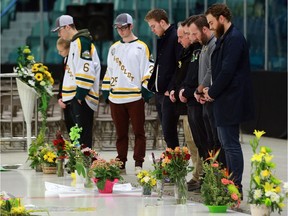 NHL player Connor McDavid (centre) visits the on ice memorial at the Elgar Peterson Arena to pay his respects to the Humboldt Broncos hockey players who lost their lives in a bus crash in Humboldt, Sask., on April 17, 2018.