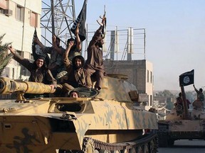 In this undated file image posted by the Raqqa Media Centre, ISIL fighters ride tanks during a parade in Raqqa, Syria.