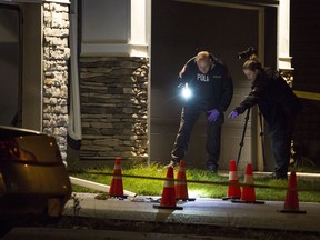 CALGARY, AB -- Police investigate evidence marked by pylons in the driveway after a shooting on Redstone Manor NE in Calgary, on September 20, 2016. -- (Crystal Schick/Postmedia)