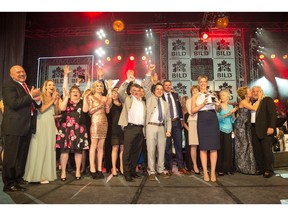 Calbridge Homes celebrates on stage at the BILD Calgary Region Awards. President and CFO Bev Higham-Linehan holds the trophy.