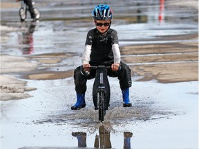 The nearly record-setting highs Calgary is enjoying this week are about to followed by a significant snowfall. Vincent, 5, geared up with snow pants and rubber boots to have fun run-biking through puddles on St. George's Island on a spring Saturday in Calgary, April 14, 2018. (Gavin Young/Postmedia)