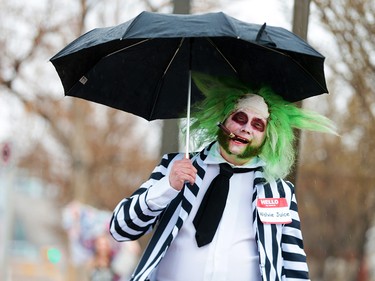Beetlejuice aka John Gibson takes shelter from the rain as he heads towards the Calgary Expo at Stampede Park on Sunday, April 29, 2018.