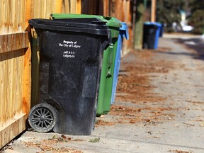 A black cart (foreground) is shown with compost and recycle bins in an alley in the Elboya community in southwest Calgary Wednesday, April 18, 2018. Jim Wells/Postmedia