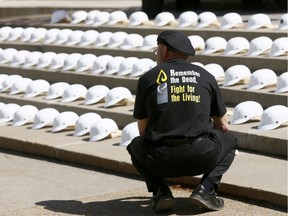 John Leeyus, of UFCW Local 401, inspects the 166 helmets displayed at a ceremony and memorial service at Edward Place Park at City Hall in recognition of National Day of Mourning in Calgary on Saturday.