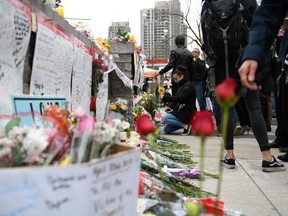 People leave flowers at a memorial on Yonge Street the day after a driver drove a rented van down sidewalks Monday afternoon, striking pedestrians in his path in Toronto, Tuesday, April 24, 2018.