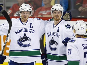 Vancouver Canucks' Henrik Sedin, left, from Sweden, celebrates his goal with his brother Daniel Sedin during third period NHL hockey action against the Calgary Flames in Calgary, Wednesday, Oct. 7, 2015.THE CANADIAN PRESS/Jeff McIntosh