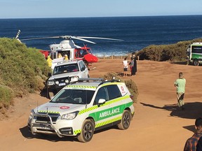 A rescue helicopter and other emergency vehicles at the scene of a shark attack in Gracetown, Australia, Monday, April 16, 2018. A surfer mauled by a shark Monday managed to swim to shore despite serious injuries to both of his legs, an official and a witness said.