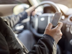 Using a phone in a car texting while driving concept for danger of text message and being distracted. Getty Images/iStockphoto