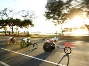 Tristan Smyth of Canada, John Smith of England and Simon Lawson of England compete just after sunrise in the T54 marathon at the 2018 Commonwealth Games in Australia on April 15, 2018.