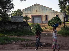 Women carry leaves of manioc (cassava) past the power plant that has shut down in Mbandaka, northwest of Democratic Republic of the Congo, on May 23, 2018.  The Ebola vaccination campaign launched in the remote locations of Mbandaka and Bikoro in rural northwestern DRC is challenged by a lack of electricity and gasoline supply, AFP reports.   / AFP PHOTO / Junior D. KANNAHJUNIOR D. KANNAH/AFP/Getty Images
