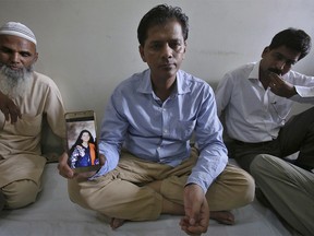 Abdul Aziz Sheikh, center, father of Sabika Sheikh, a victim of a shooting at a Texas high school, shows a picture of his daughter in Karachi, Pakistan, Saturday, May 19, 2018. The Pakistani foreign exchange student is among those killed in the shooting, according to a leader at a program for foreign exchange students and the Pakistani Embassy in Washington, D.C.  Megan Lysaght, manager of the Kennedy-Lugar Youth Exchange & Study Abroad program (YES), sent a letter to students in the program confirming that Sabika Sheikh was killed in the shooting. (AP Photo/Fareed Khan) ORG XMIT: ISL101