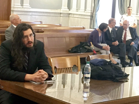 Michael Rotondo, left, sits during an eviction proceeding in Syracuse, N.Y., brought by his parents, Mark and Christina, seen speaking with their lawyer in the court gallery behind.