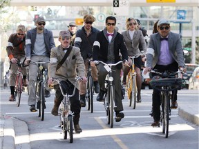 Participants in Calgary's annual Tweed Ride cycle along the 7th street cycle track in downtown in 2015.