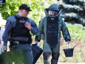 Police tactical team members deal with a grenade that was found buried in a back yard in lower Mount Royal on Saturday afternoon. A family was digging out a stump at a home in the 1900 block of 12th Street S.W. when they uncovered the grenade.