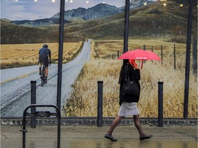 Not so different from May 1, 2018, a pedestrian passes by a mural of the Rocky Mountains as a rain shower falls in Calgary, on May 2, 2017. Forecasts for the Calgary area are calling for sun and higher temperatures in the high teens for the rest of the week.