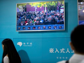 Visitors look at a demonstration of electronic facial-recognition technology at the 21st China Beijing International High-tech Expo in Beijing, China, Friday, May 18, 2018.