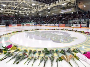 Flowers lie at centre ice as people gather for a vigil at the Elgar Petersen Arena, home of the Humboldt Broncos, to honour the victims of a fatal bus accident in Humboldt, Sask. on Sunday, April 8, 2018. The Humboldt Broncos hockey team has resolved a dispute with its own league over the #HumboldtStrong slogan.