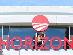 Hugh Williams, from National Neon Signs, adjusts signage at the entrance of the New Horizon Mall located north of Calgary on Thursday, May 3, 2018.