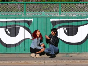 Pricila Noriega-Lessard (L) and her sister Jess Noriega-Lessard have an impromptu smartphone photo shoot on 9a St NW near 2 Ave in Calgary Saturday. Jim Wells/Postmedia