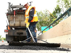 Calgary Mayor Naheed Nenshi operates heavy equipment as he works on filling a pothole with City crews during a visit to a road crew filling potholes on 14th Street N.W. in Calgary on Tuesday, May 29, 2018. Crews have been out since early April and have filled more than 3,500 in the past two months.