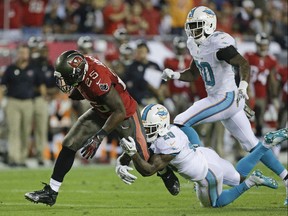 Running back Mike James, in his rookie season with the Tampa Bay Buccaneers, is tackled by Miami Dolphins free safety Reshad Jones after gaining 24 yards during the first half of an NFL game in Tampa, Fla., on Nov. 11, 2013.
