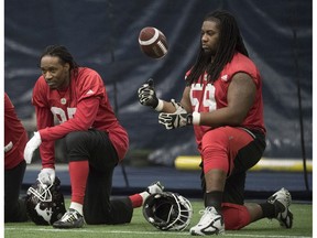 Calgary Stampeders Joe West (left) and Randy Richards sit on the sidelines at practice for the 104th Grey Cup in Toronto on Wednesday, November 23, 2016.
