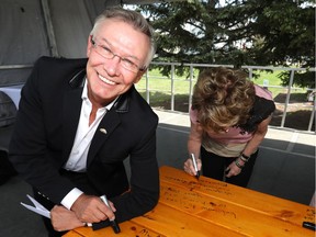 Jay Westman, CEO of Jayman Built, signs a picnic table at the ground-breaking for the Clayton, the latest building for the Resolve Campaign.