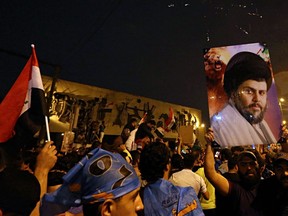 Followers of Shiite cleric Muqtada al-Sadr, seen in the poster, celebrate in Tahrir Square, Baghdad, Iraq, early Monday, May 14, 2018.
