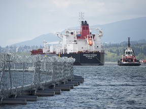 An oil tanker passes a floating chain link fence topped with razor wire at the Kinder Morgan marine terminal in Burrard Inlet just outside of metro Vancouver on May, 1, 2018.