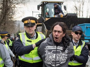 A protester is led away by RCMP officers at a protest against the Kinder Morgan Trans Mountain pipeline expansion.