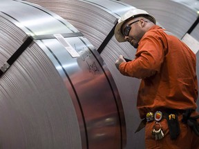 A Dofasco employee looks at rolls of coiled steel in Hamilton Ont., March 13, 2018. The Trump administration says it will go ahead with plans to hit Canada, Mexico and the European Union with hefty tariffs on steel and aluminum, effective midnight Thursday night.