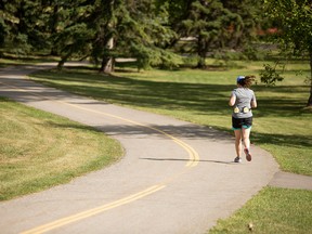 A runners strides along a path in Confederation Park.