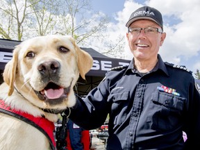 Tom Sampson, director of the Calgary Emergency Management Agency, mugs for a photo with Canada Task Force 2 National Disaster Response Team dog Hunter during Disaster Alley at McMahon Stadium in Calgary, Alta., on Saturday, May 9, 2015.