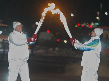 Frank King hands the torch off to Diane Allen after crossing the 10th Street bridge as the Olympic Torch Relay makes it's way through pre-dawn Calgary Tuesday morning January 19, 2010. (Ted Rhodes/Calgary Herald)