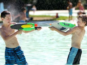 Brothers Braiden May, left, and Ryder enjoy a water fight at the Riley Park wading pool on a hot August day in 2014.